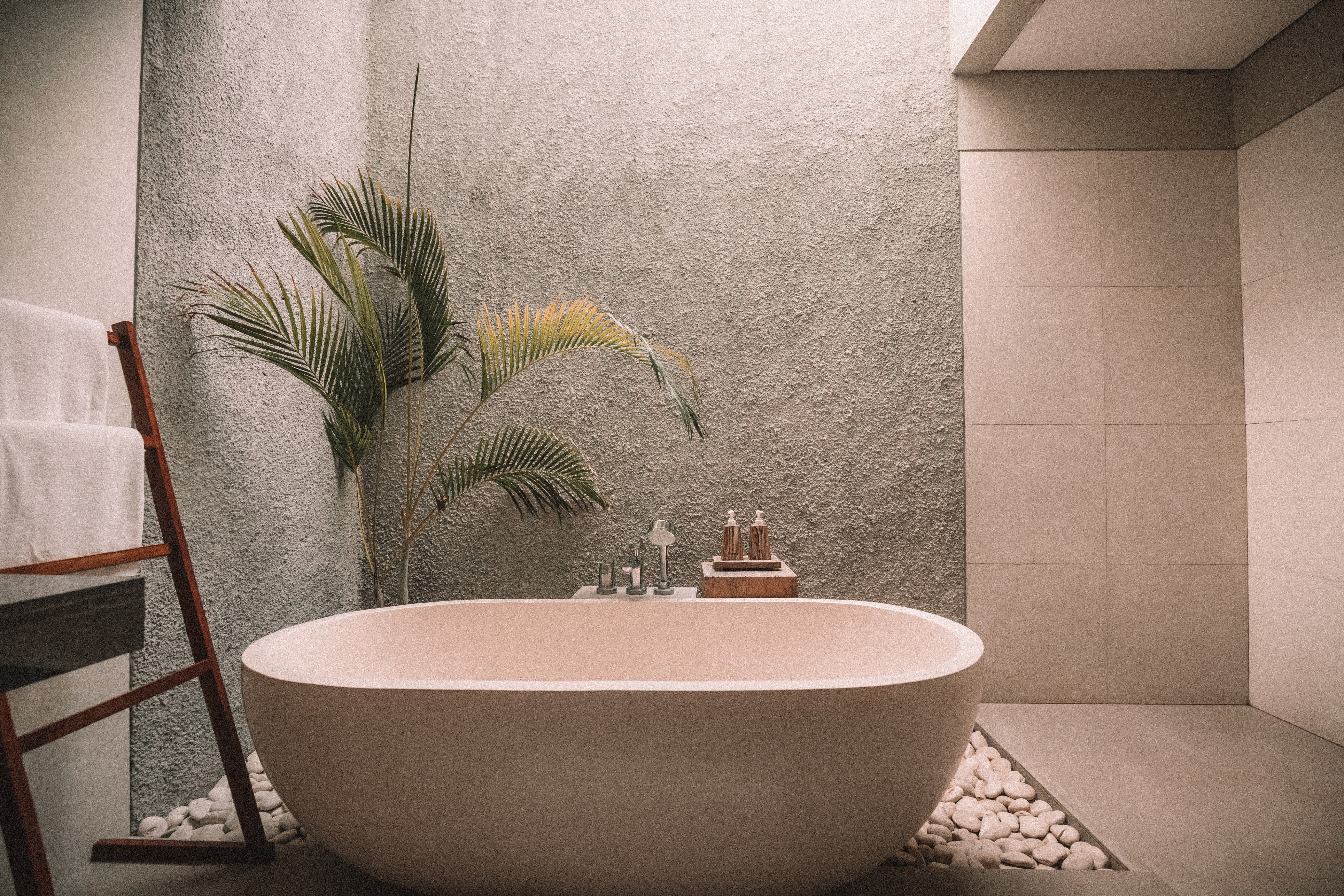 a tranquil room containing a large bath tub in warm, neutral colours